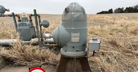 : A well measuring tape is positioned next to an irrigation well head in preparation for making a water level measurement.
