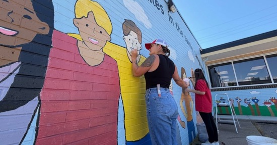 Lanna VanWinkle and Hailey Dupler retouch a mural at Literacy Council of Grand Island as part of a group from Lisa Willman State Farm.
